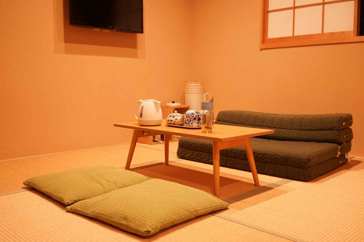 Stanza tatami con tavolino basso, set da tè e divano.